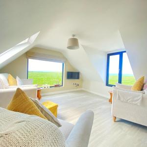 Ático con sala de estar con muebles blancos y ventanas grandes. en Luxury holiday rental with sea views on the Wild Atlantic Way, en Tralee