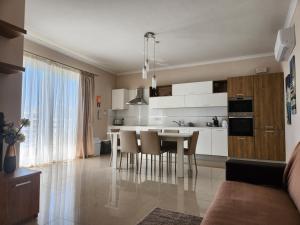 een keuken met witte kasten en een tafel en stoelen bij Riviera Holiday Apartments - Seafront - Wifi in Marsaskala