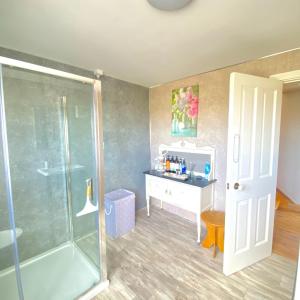 a bathroom with a shower and a sink and a desk at Luxury holiday rental with sea views on the Wild Atlantic Way in Tralee