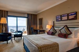 a hotel room with a bed and a balcony at Corinthia St George's Bay in St. Julianʼs