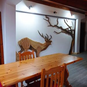 a wooden table in front of a wall with a deer mural at L'angolo del buonumore in Daone