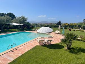 a swimming pool in a yard with an umbrella at Appartamento Dragunara in Alghero