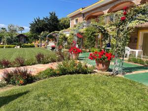 a garden with red flowers in pots in front of a house at Appartamento Dragunara in Alghero