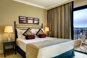 a hotel room with a bed and a balcony at Corinthia St George's Bay in St. Julianʼs