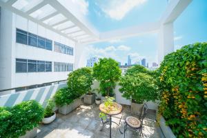 einen Balkon mit Tischen und Bäumen auf einem Gebäude in der Unterkunft Babylon Serviced Apartment in Ho-Chi-Minh-Stadt