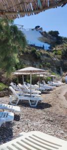 a group of lounge chairs and umbrellas on a beach at Koralli Sea View Hotel in Kato Achaia