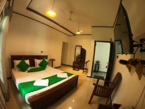 ein Schlafzimmer mit einem Bett mit grünen Kissen und einem Spiegel in der Unterkunft OYO KINGS HOTEL in Katunayaka