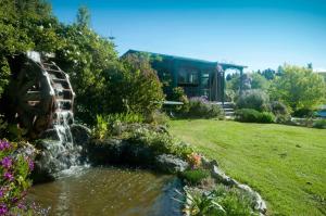 a garden with a waterfall in front of a house at Waterwheel Cottage in Upper Moutere