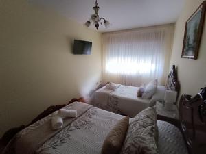 1 dormitorio con 2 camas y ventana en Baixo a Lua Rooming en Sarria