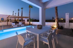 a patio with a table and chairs next to a swimming pool at Salty Sun Luxury Villas in Kremasti +40 photos