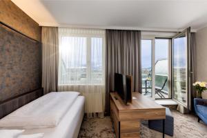 ウィーンにあるホテル アム パークリングのベッドと大きな窓が備わるホテルルームです。