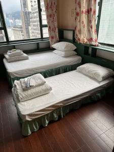 three beds sitting in a room with windows at USA Hostel HONG KONG in Hong Kong