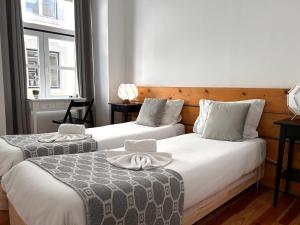 2 Betten in einem Zimmer mit 2 Fenstern in der Unterkunft 262 Baixa Guesthouse in Lissabon