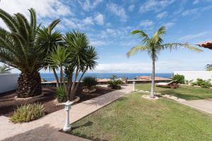 um jardim com palmeiras e o oceano ao fundo em Villa Charly em Puerto de la Madera