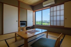 a room with a table and chairs and windows at Fufurotenburonoyado Ginsyou in Ibusuki