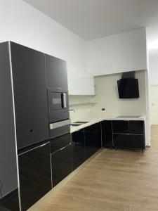 a kitchen with black and white cabinets and a microwave at Gold apartament vlore free parking in Vlorë