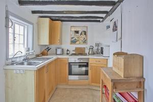 a kitchen with a sink and a stove at Old Post Office Cottage in Walberswick