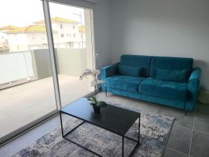 un soggiorno con un divano blu e un tavolo di New villa 5mn from the beach-Pyrenees view a Sainte-Marie-la-Mer