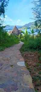 a stone path leading down to a beach with a thatched building at Paradise Eco-Hub in Kabale