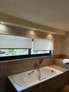a bath tub in a bathroom with a window at Holiday Village - Swimming pool apartments in Kamena Vourla