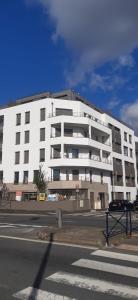 ein großes weißes Gebäude am Straßenrand in der Unterkunft Charme Citadin in Villemomble + 35 Fotos