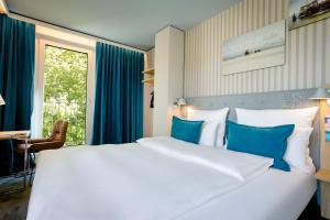 a bedroom with a large white bed with blue pillows at Motel One Rostock in Rostock