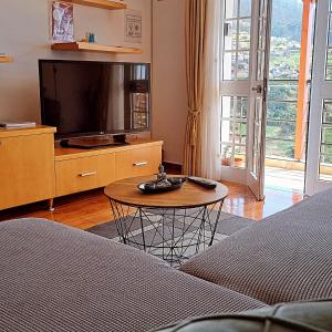 - un salon avec une télévision et une table dans l'établissement Orchid House Madeira, à Calheta