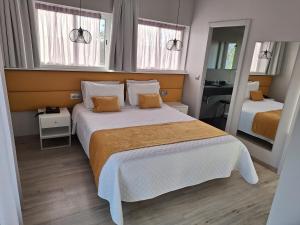 a bedroom with a large bed and two windows at Hotel Aleluia in Fátima