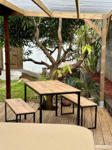 圣若瑟Bungalow cosy, tout confort的野餐桌和长椅,在树荫下的甲板上