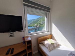 a bedroom with a large window and a television at Visit Drežnica in Mostar