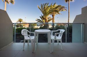 una mesa blanca y sillas en un balcón con palmeras en Smartr Maspalomas Corinto en Playa del Inglés