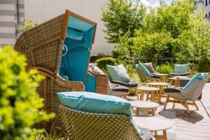 a row of wicker chairs and tables on a patio at Motel One Rostock in Rostock
