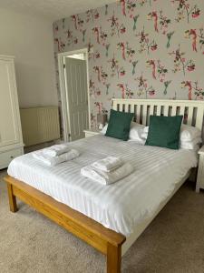 - une chambre avec un grand lit blanc et des oreillers verts dans l'établissement The Coldstreamer, à Gulval