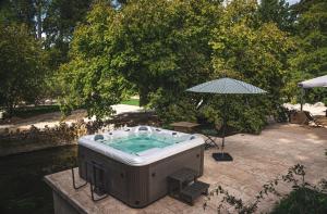 - un bain à remous installé sur une terrasse avec un parasol dans l'établissement Domaine de Neuvon, à Plombières-lès-Dijon