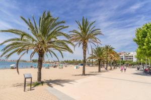 a beach with palm trees and people on it at Monaco 1A Puerto Roses - Barneda in Roses