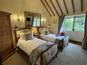 a bedroom with two beds and a mirror and a window at Guiting Guest House in Guiting Power