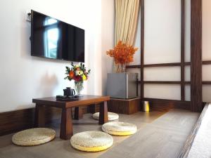 a living room with a table and a tv on the wall at Free Style Hotel Dalat in Da Lat