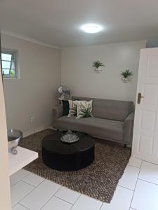 una sala de estar con un sofá y una mesa en Innes Self-catering Apartment, en Bloemfontein