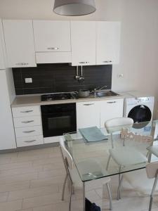 a kitchen with a glass table and white cabinets at Casa Vacanze condominio I Giardini, Pula in Pula