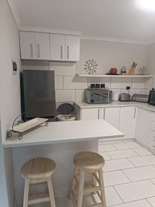 cocina con encimera y 2 taburetes en Innes Self-catering Apartment, en Bloemfontein