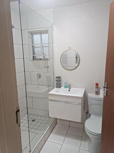 Un baño blanco con lavabo e inodoro. en Innes Self-catering Apartment, en Bloemfontein