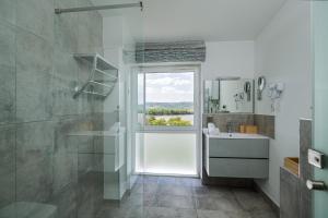 baño con ducha, lavabo y ventana en Akvarell Apartmanház en Zebegény