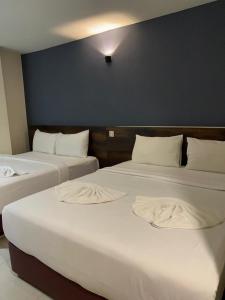 2 bedden in een hotelkamer met witte lakens bij HOTEL SRI SUTRA (BANDAR SUNWAY) in Petaling Jaya