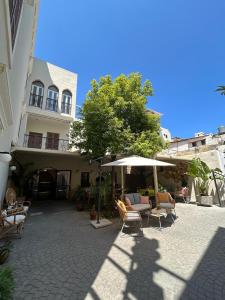 eine Terrasse mit Stühlen und einem Sonnenschirm vor einem Gebäude in der Unterkunft VICTORIA BOUTIQUE HOTEL in El Mîna