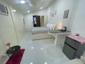 a small white room with a bed and a desk at Pinkys Guest House in Allen