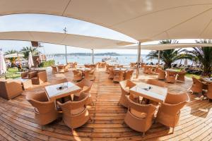 Grand Hotel Portoroz 4* superior – Terme & Wellness LifeClass في بوروتوروج: مطعم بطاولات وكراسي ومظلة