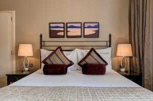 a bedroom with a white bed with two lamps at Corinthia St George's Bay in St. Julianʼs