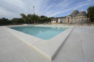 a large swimming pool with blue water in a courtyard at I trulli di Eva in Noci