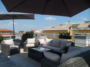 a patio with a couch and chairs and an umbrella at Residhome Arcachon Plazza in Arcachon