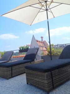 two wicker chairs and an umbrella on a patio at Residhome Arcachon Plazza in Arcachon